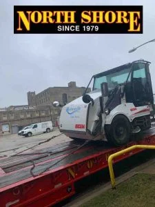 Street cleaner coming off tow services lowboy